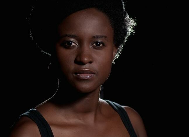Poet Tjwangwa (TJ) Dema faces the camera with a serious expression, standing in front of a black background